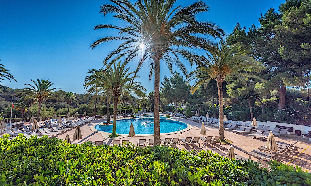 Udsigt til poolområdet omringet af palmer på Grupotel Club Cala Marsal i Portocolom.