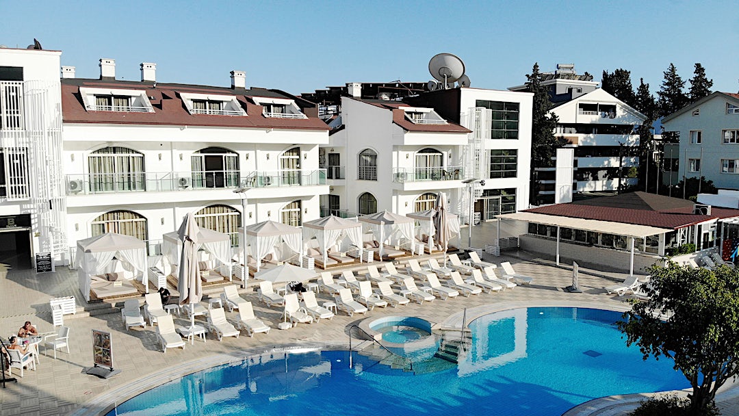 Hotellets facade i baggrunden med pool og liggestole i forgrunden.